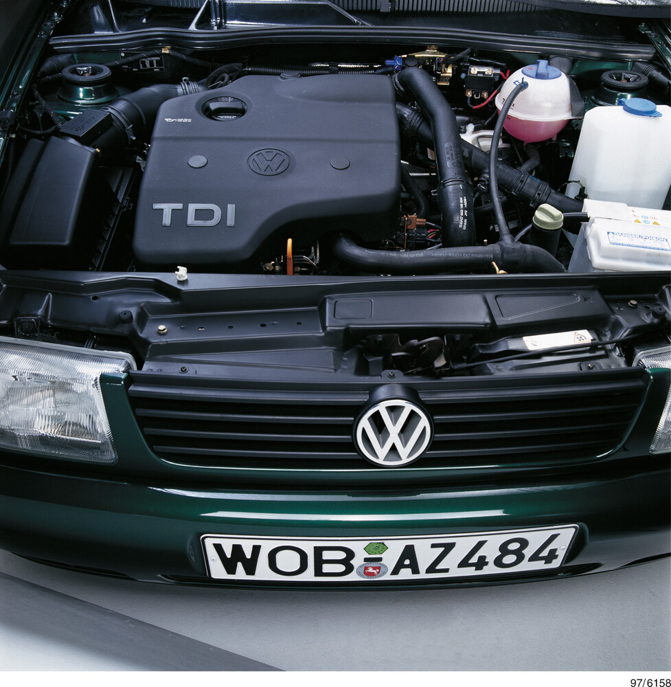 Motor s nápisom TDI pod otvorenou kapotou zeleného auta VW